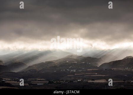 Les rayons du soleil brillent à travers les nuages de tempête à l'aube sur les contreforts et les montagnes en Guia de Isora, sur l'ouest de Tenerife, Canaries, Espagne Banque D'Images