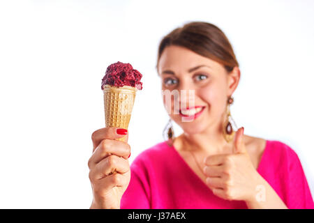 Smiling woman gesturing thumb up, vêtu d'un chemisier rose, et la tenue de la glace cornet gaufré looking at camera. Isolé sur blanc. Banque D'Images