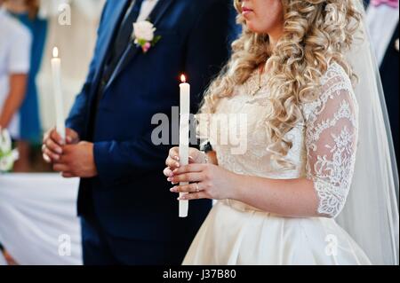 Wedding couple holding brûler des bougies à l'église cérémonie.a Banque D'Images