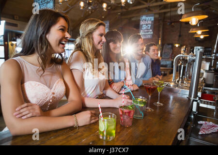 Happy friends sitting par boissons sur comptoir de bar Banque D'Images