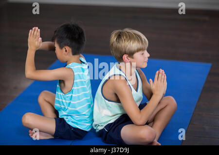 Vue latérale du yoga à la maison des frères et sœurs Banque D'Images