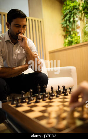 Young Woman playing chess with female colleague in office Banque D'Images