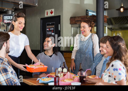 Groupe d'amis à la recherche à waitress in restaurant Banque D'Images