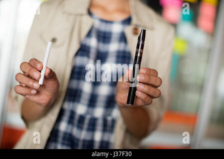 La mi-section de female executive holding electronic cigarette in office Banque D'Images