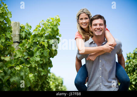 Portrait of happy young couple dos au vignoble contre le ciel bleu Banque D'Images