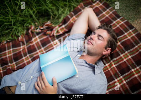 High angle view of man with book sleeping on blanket Banque D'Images