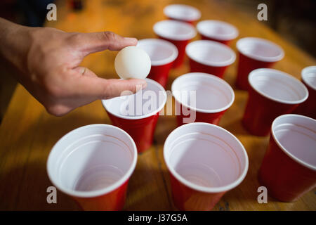 La main coupée de l'homme jouant en bar Beer Pong Banque D'Images