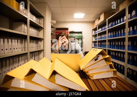 Businessman using laptop frustrés par les dossiers sur la table dans la salle de stockage Banque D'Images