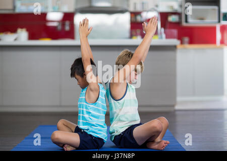 Frères et sœurs d'effectuer du yoga à la maison Banque D'Images