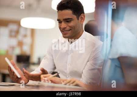 Smiling businessman discutant avec collègue sur office vu à travers le verre Banque D'Images