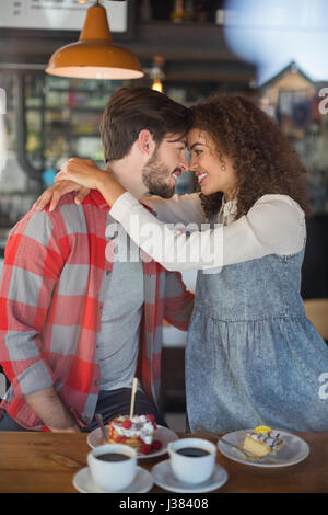 Happy young couple embracing in pub vu à travers le verre Banque D'Images