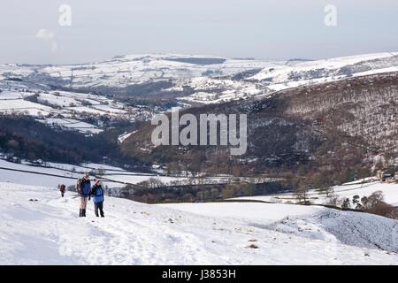 Senior couple hiking up Kinder Scout dans la neige d'hiver. Le Hayfield, Peak District, UK Banque D'Images