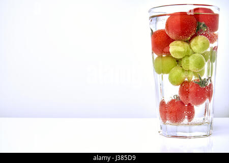 Tomates cerise et les raisins dans un verre avec waterwith copier l'espace. Banque D'Images
