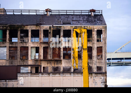 Ancienne ruine industrielle avec des fenêtres brisées, rappelle l'oeil vide, et la flèche de grue de construction Banque D'Images