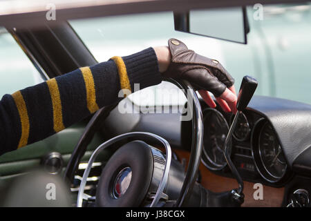 Le conducteur garde les mains dans les gants de cuir sur le volant de sa voiture d'époque Banque D'Images