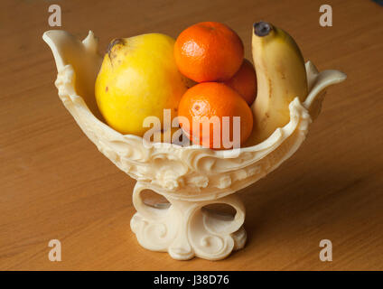 Fruits dans un élégant vase en plastique sur la table en bois Banque D'Images