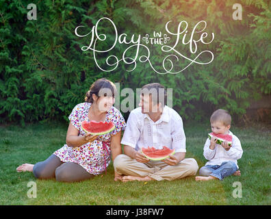 Père, mère et fils eating watermelon assis sur l'herbe et du texte journée dans la vie. Lettrage calligraphie vintage part attirer Banque D'Images