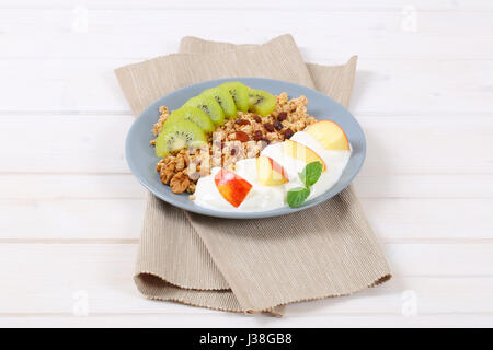 Assiette de muesli avec du yaourt et des fruits frais sur place beige mat Banque D'Images