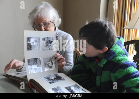 Grand-mère de 81 ans et 12 ans à la recherche d'un petit-enfant à un album photo Banque D'Images