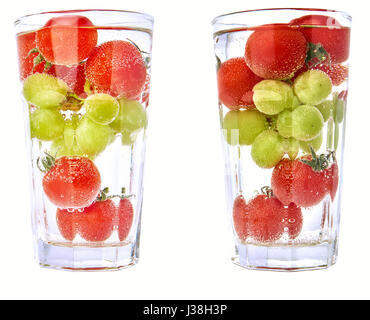 Tomates cerise et les raisins dans un verre à cocktail avec de l'eau - isolé, deux versions. Banque D'Images