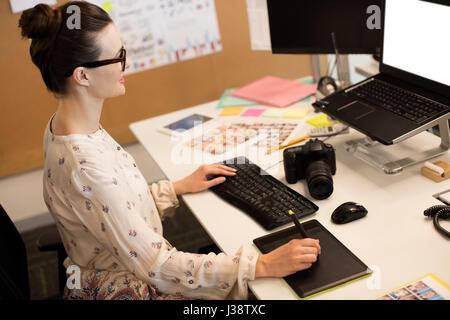 High angle view of businesswoman using computer tout en travaillant sur le numériseur at desk in office Banque D'Images