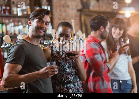 Portrait of happy couple holding drinks en bar Banque D'Images