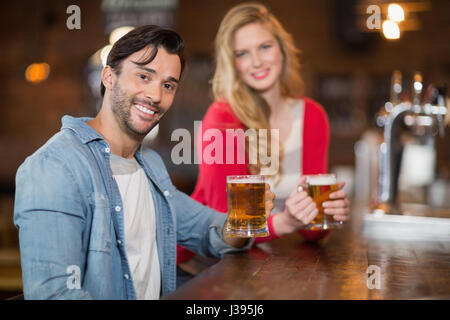 Portrait of young man and woman holding bière au pub Banque D'Images