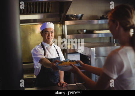 Chef passant le bac avec frites de serveuse dans la cuisine commerciale Banque D'Images