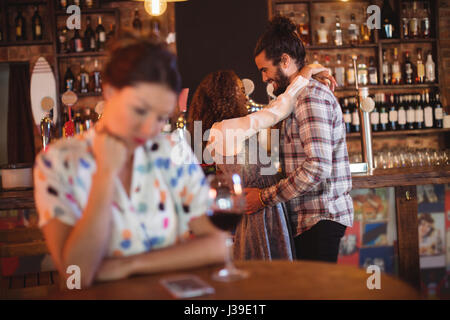 Femme jalouse ignorant affectionate couple en pub Banque D'Images
