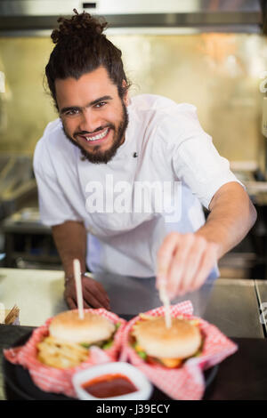 Portrait of male chef preparing burger en cuisine commerciale Banque D'Images