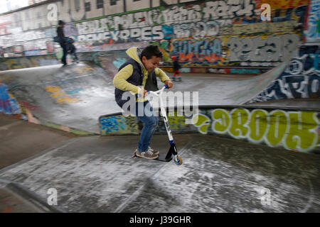 10-year-old boy riding a scooter dans un skate park Banque D'Images