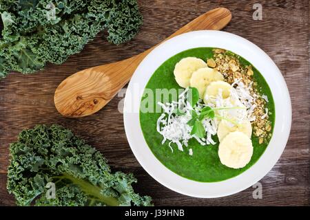 Smoothie vert bowl with kale, bananes, céréales, et noix de coco. Scène de frais généraux sur bois rustique. Banque D'Images