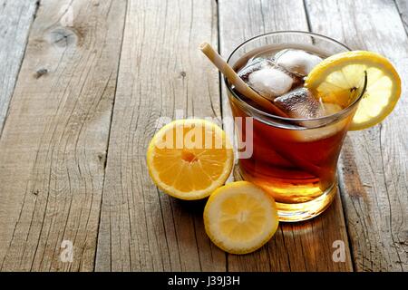 Verre de thé glacé au citron fait maison avec de la paille sur un fond de bois rustique Banque D'Images