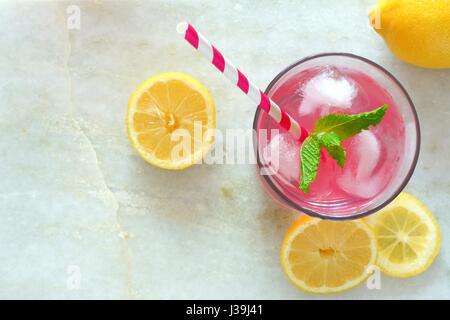 Verre de limonade rose à la menthe et de tranches de citron vue aérienne sur un arrière-plan en marbre blanc Banque D'Images