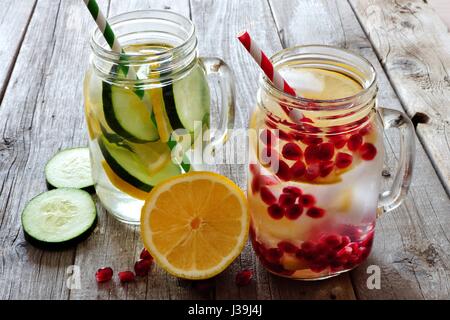 Dans l'eau Detox pot Mason verres avec le citron, le concombre et la grenade contre un arrière-plan en bois rustique Banque D'Images