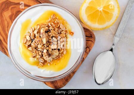 Bol de Yogourt aromatisé au citron et granola, les frais généraux en marbre blanc sur scène Banque D'Images