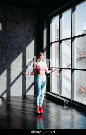 Concept de remise en forme. Mode de vie sain. Jeune femme sautant slim avec la corde à sauter dans la salle de sport Banque D'Images