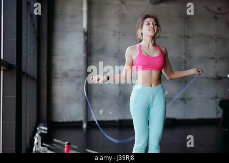 Concept de remise en forme. Mode de vie sain. Jeune femme sautant slim avec la corde à sauter dans la salle de sport Banque D'Images