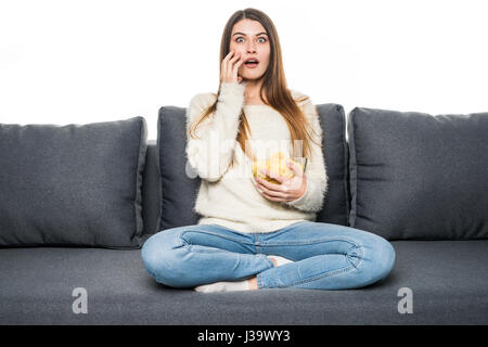 Young woman watching TV and eating chips Banque D'Images