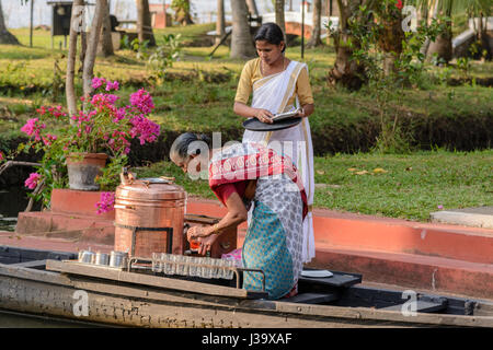 Les femmes en saris Keralan préparer le thé sur un bateau pour les invités au Coconut Lagoon Resort, Kottayam, Kavanattinkara, Kumarakom, Kerala, Inde du Sud, en Asie du Sud Banque D'Images