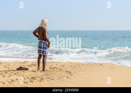 L'homme indien local portant un foulard donne sur la mer de la plage de Chowara, au sud de Kovalam, Kerala, Inde du Sud, en Asie du Sud Banque D'Images