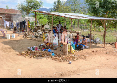 Un Tamoul tribal family s'asseoir à l'ombre à leur domicile en milieu rural dans les plaines agricoles du Tamil Nadu, Inde du Sud, en Asie du Sud Banque D'Images