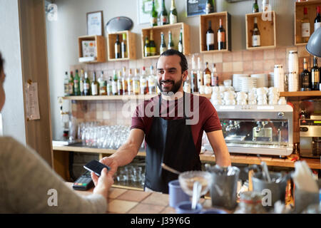 Barman et femme avec lecteur de carte et smartphone Banque D'Images