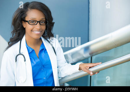 Closeup portrait portrait of smiling confident female amical, professionnel de la santé avec un sarrau, lunettes, et stéthoscope. L'interface de l'hôpital isolé Banque D'Images