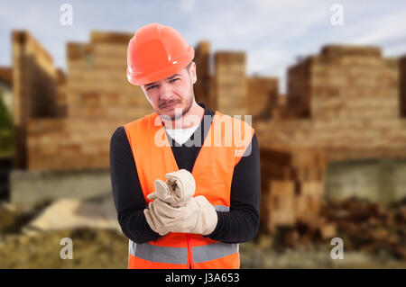 Homme builder avec douleur du poignet après accident de travail sur le lieu de construction Banque D'Images