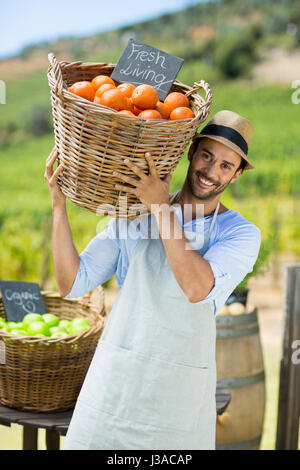 Portrait of happy farmer l'exercice par les oranges fraîches dans un récipient au marché à la ferme à vendre Banque D'Images