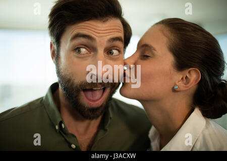Close up of woman kissing businessman in office Banque D'Images