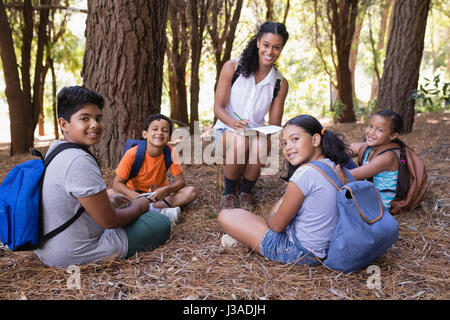 Portrait de professionnels Enseignant et élèves assis dans la forêt au cours de l'été visite Banque D'Images