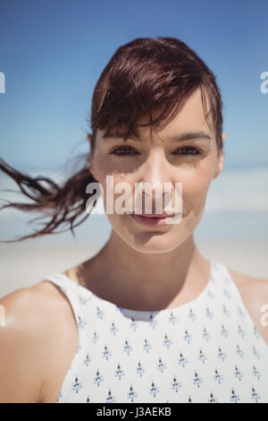 Portrait de jeune femme aux cheveux ébouriffés debout à plage en journée ensoleillée Banque D'Images