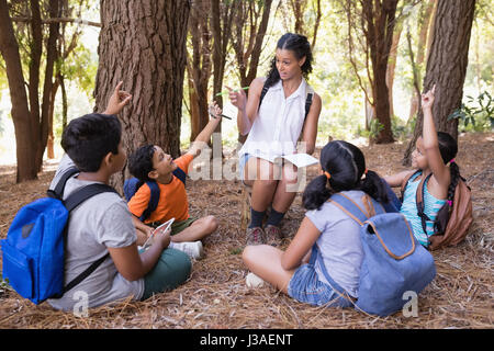 Explication de l'enseignant les élèves assis dans la forêt au cours de l'été visite Banque D'Images